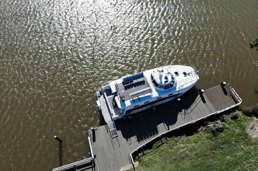 A boat docked at a pier with a grassy area beside it. 3