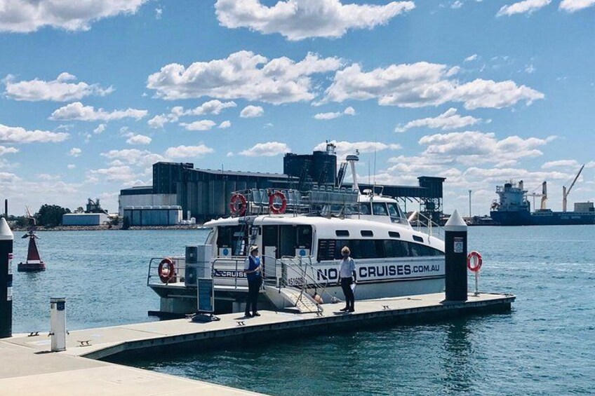 A white boat docked at a pier with a 'NO CRUISES' sign, a lifebuoy, and a person standing on the dock. 5