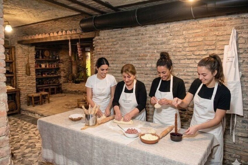 Four people in a rustic kitchen preparing food with wooden utensils and bowls. 1