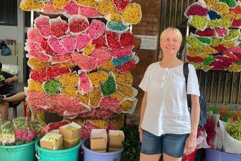 A person standing in front of a wall of colorful flower arrangements. 4