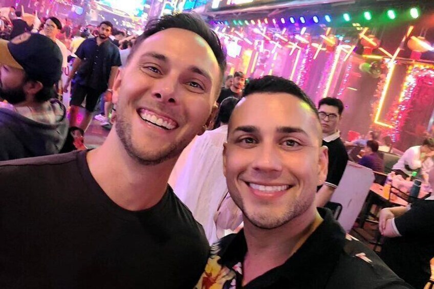 Two people in a crowded indoor setting with bright lights and decorations. 1