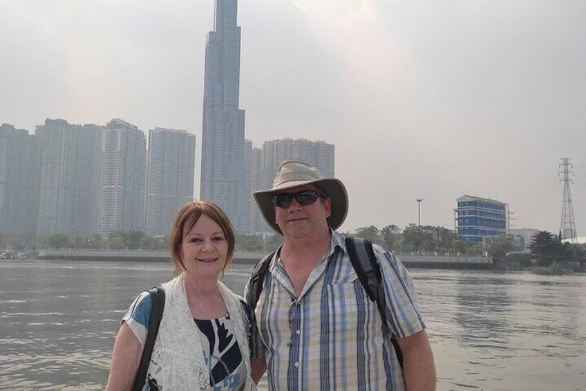 Two people standing by a body of water with a city skyline in the background. 2