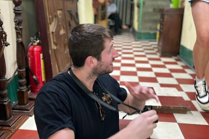 A person sitting on a red and white checkered floor, holding a camera. 5