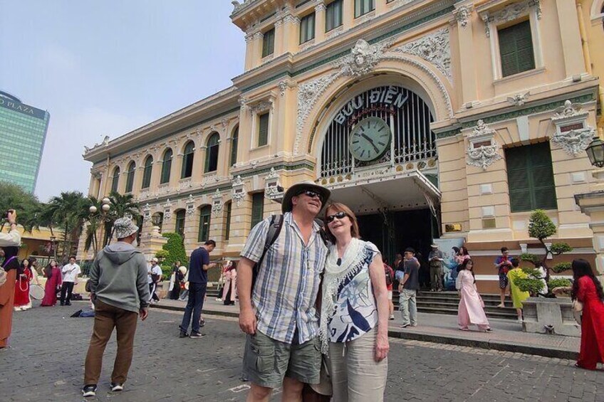 A couple posing in front of a historic building with ornate architecture and a clock. 3