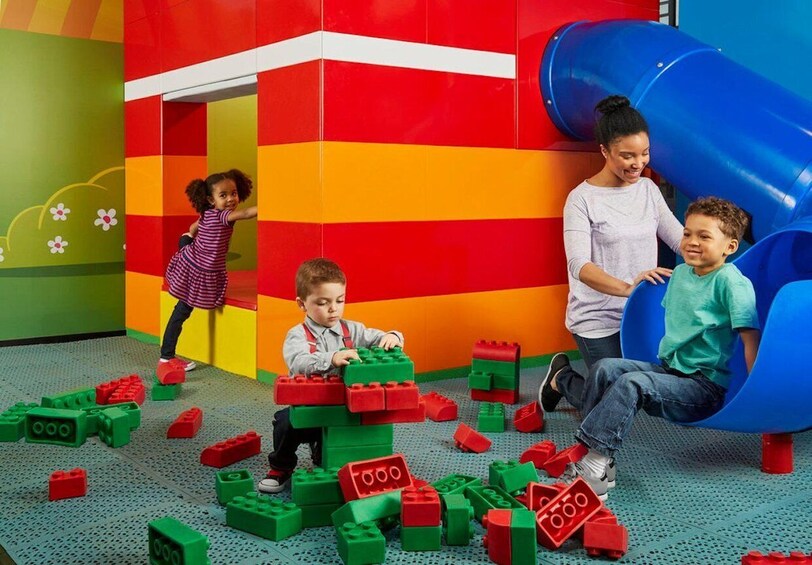 Children playing with building blocks in a colorful indoor play area with a slide. 2