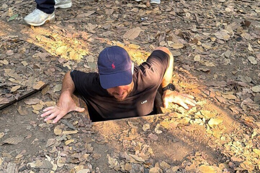 A person lying on the ground in a wooded area with dry leaves. 1