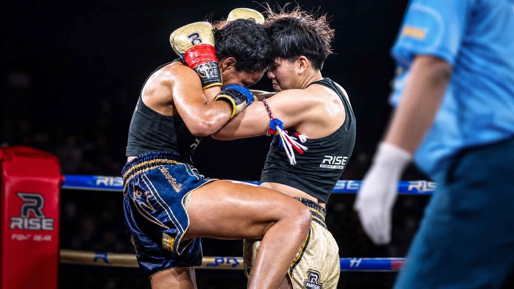 Two fighters in a boxing ring, one in blue shorts and the other in black, engaged in a match. 5