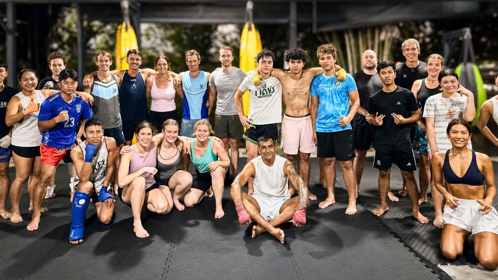 A group of people in athletic wear posing on a mat with flags in the background. 4