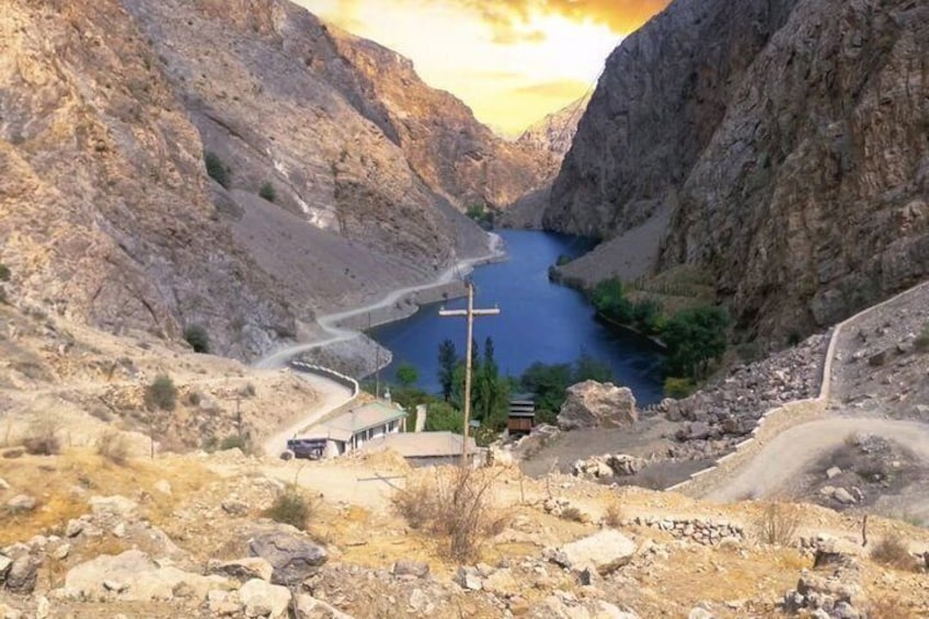 A mountainous landscape with a winding road, a small building, and a cross. 1