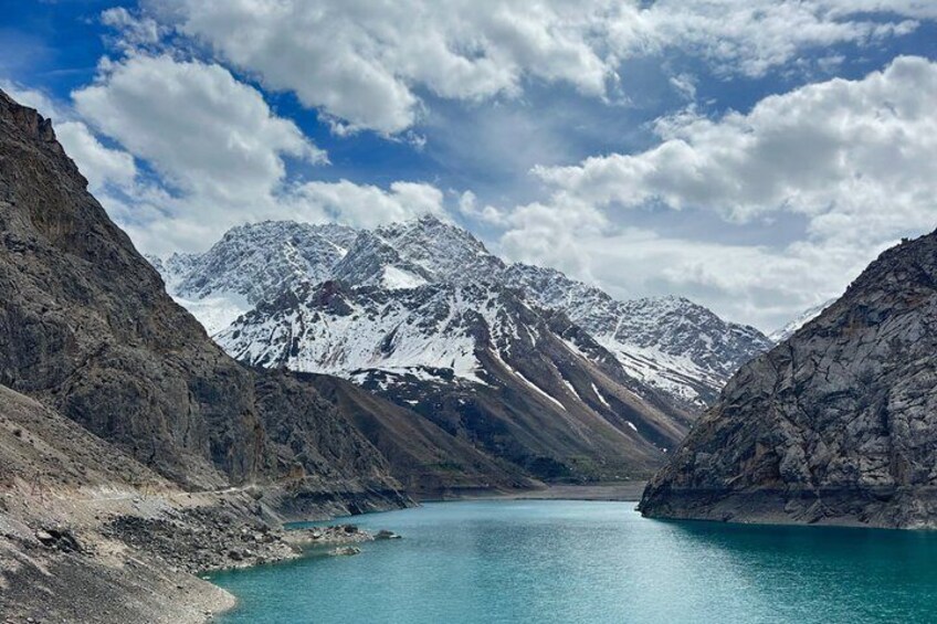 A turquoise lake surrounded by rugged mountains under a partly cloudy sky. 2