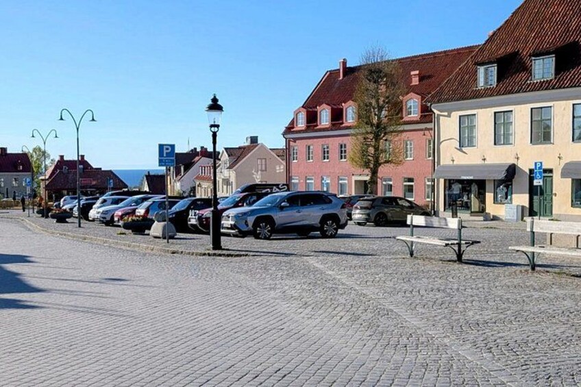 A cobblestone street lined with parked cars and traditional buildings. 5