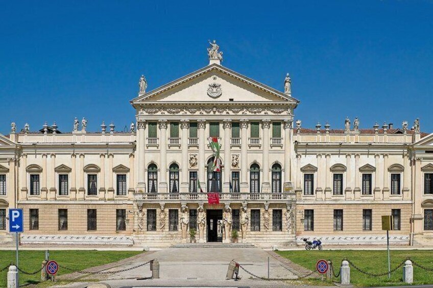A large neoclassical building with a central entrance, columns, and statues. 5