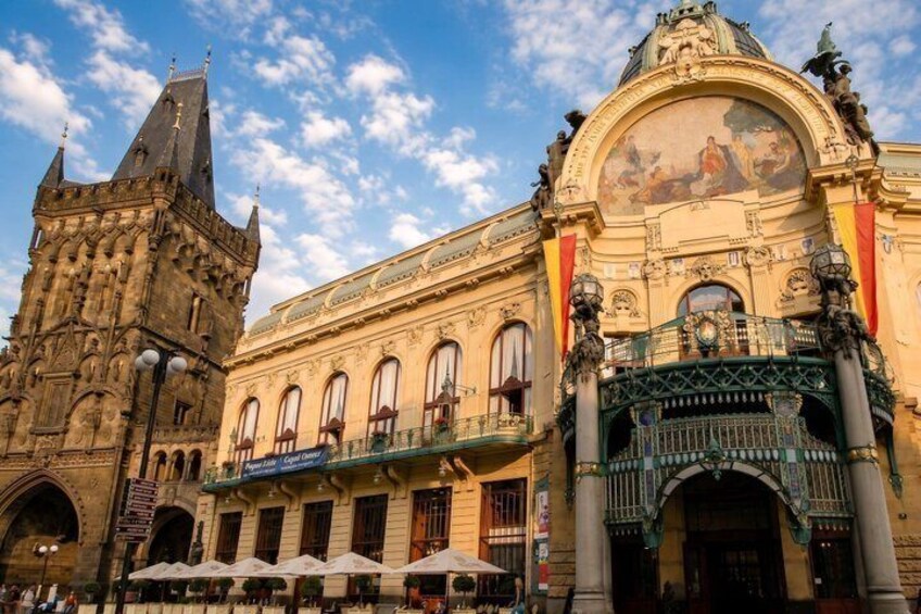 A historic building with ornate architecture, a tower, and a balcony with umbrellas. 4