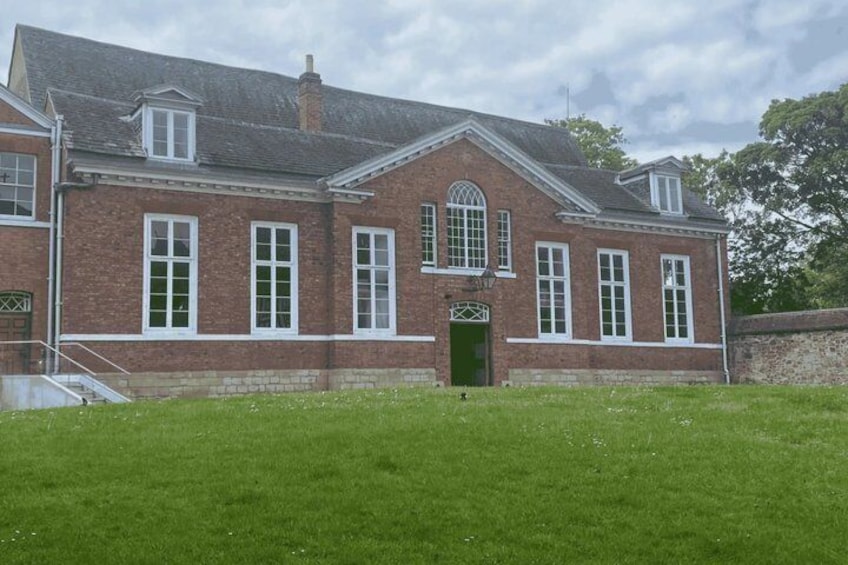 A red brick building with a green door, white window frames, and a small staircase leading to the entrance. 5