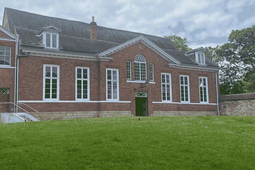 A red brick building with a green door, white window frames, and a small staircase leading to the entrance. 4