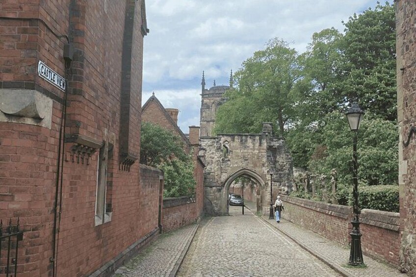 A cobblestone street, a brick building labeled 'Castle Hill,' and a stone archway. 3
