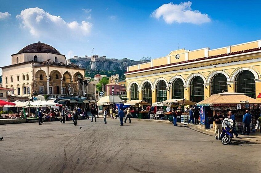 A bustling square with historic buildings, a prominent dome, and a hill in the background. 3