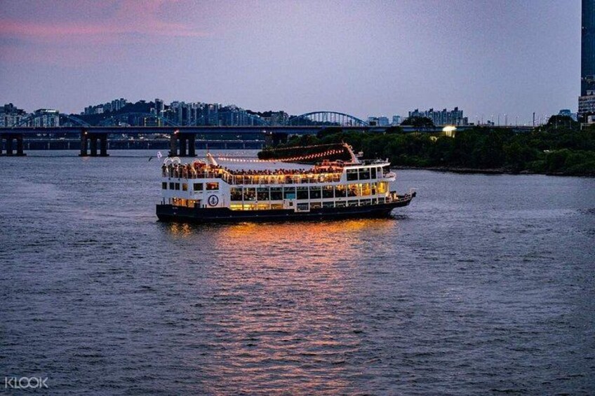 A riverboat with passengers, a bridge, and a city skyline in the background. 4