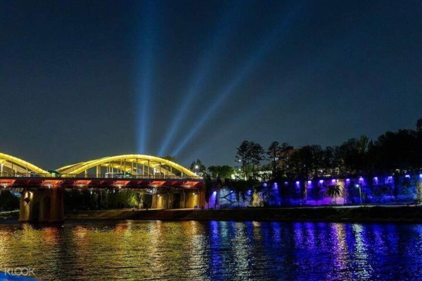 A bridge with illuminated arches and a water body reflecting lights. 5