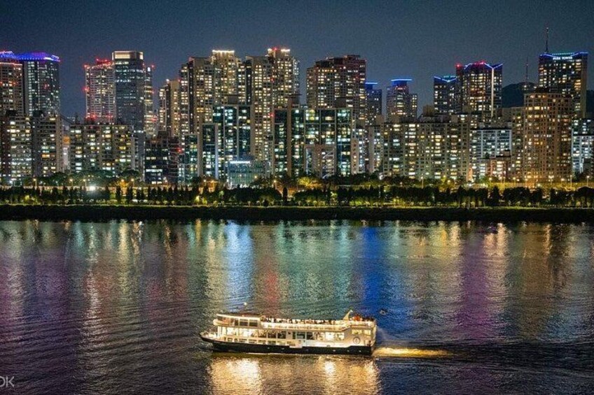 A city skyline at night with illuminated buildings reflected in the water. 2