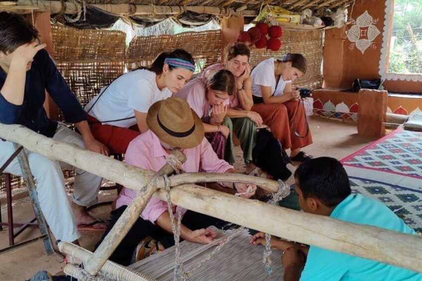 A group of people engaged in weaving on a loom. 2