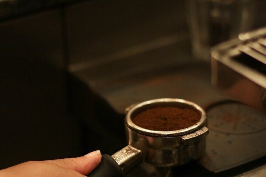 A hand holding a coffee grinder with a metal container of ground coffee. 4