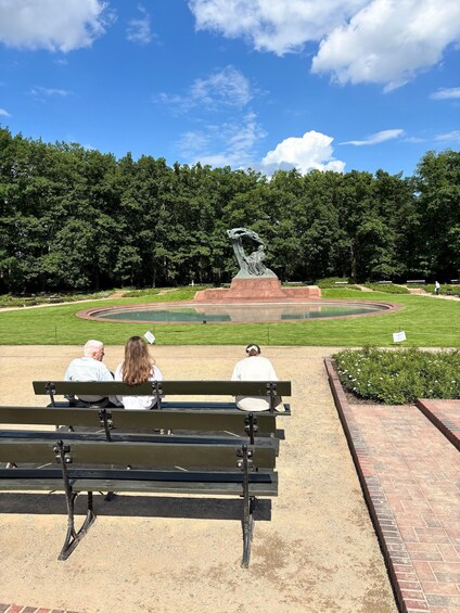 A park with a statue, benches, and a well-maintained lawn. 1