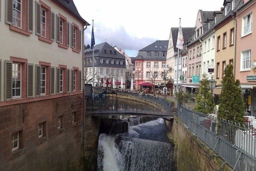 A town with a waterfall, a bridge, and traditional buildings. 2