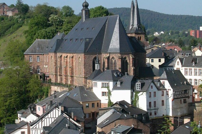 A church with a steep roof and a bell tower, surrounded by traditional houses with sloped roofs. 4