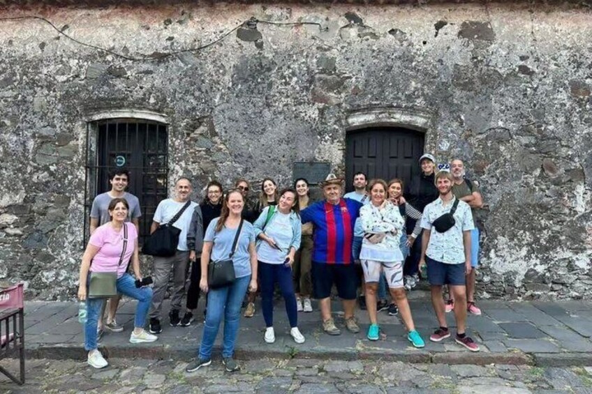 A group of people standing in front of a weathered stone wall with two doors. 3