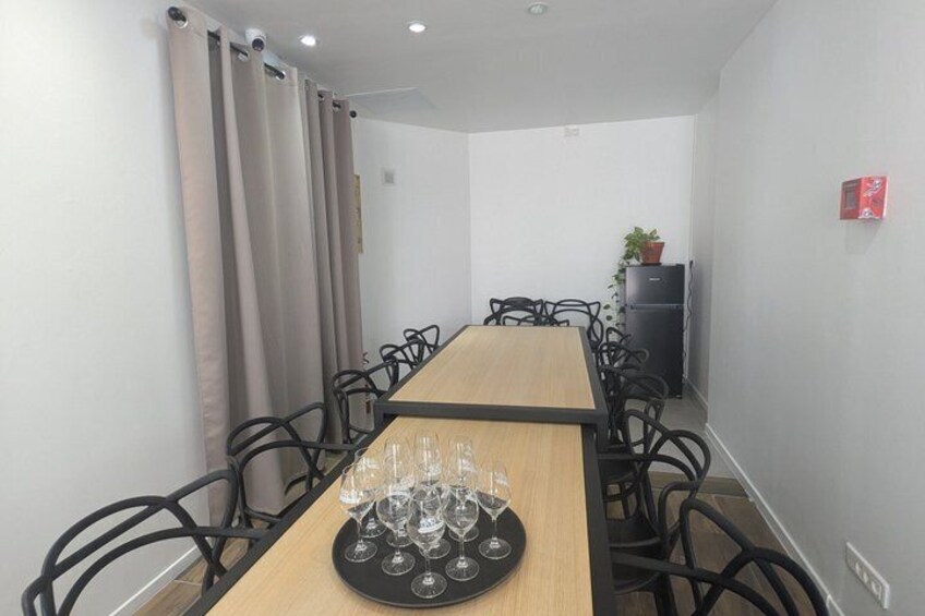 A conference room with a long table, chairs, and a tray of wine glasses. 5