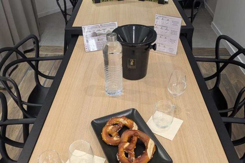 A wooden table with pretzels, a water bottle, and a black thermos. 2
