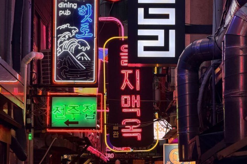 Neon signs in Korean characters, a wave graphic, and a green sign with white text. 5