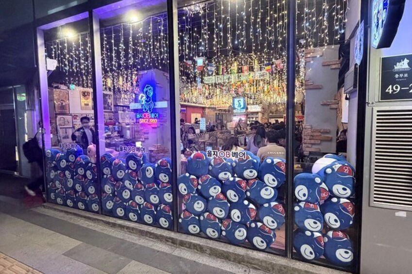 A brightly lit storefront with a glass facade, decorated with hanging lights and featuring a blue bear pattern on the lower half. 5