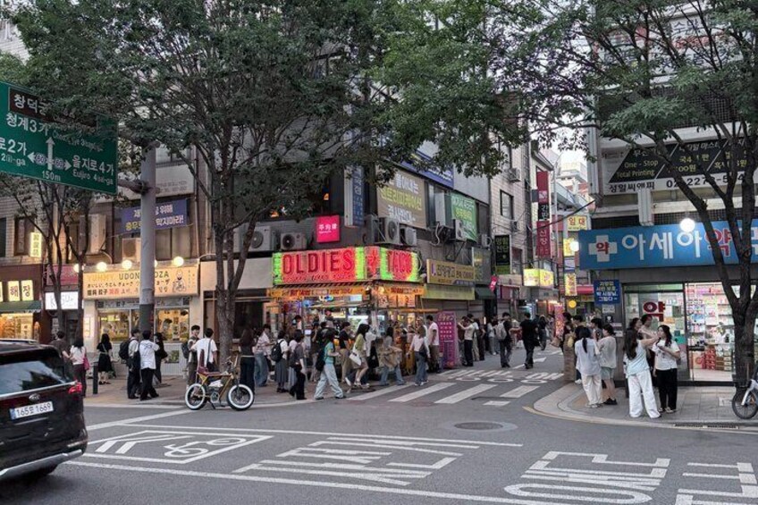 A busy urban street with pedestrians, bicycles, and cars. 2