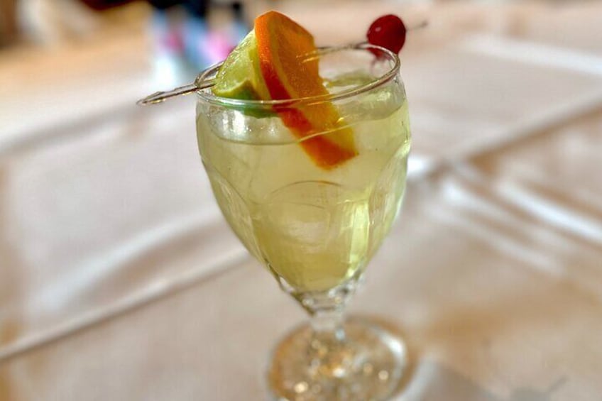 A cocktail with a slice of orange and a cherry garnish in a stemmed glass. 4