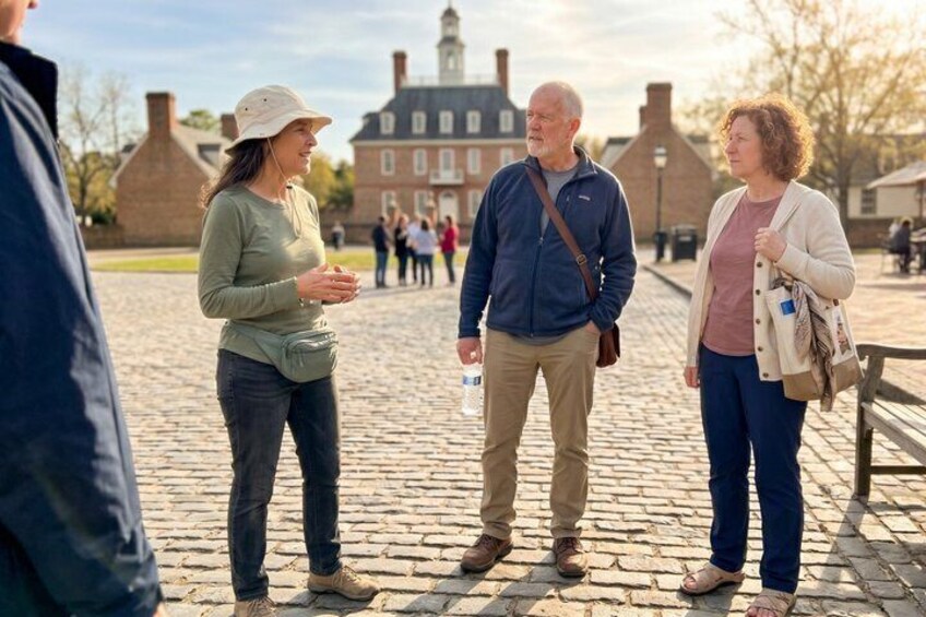Three people standing on a cobblestone street with historic buildings in the background. 2