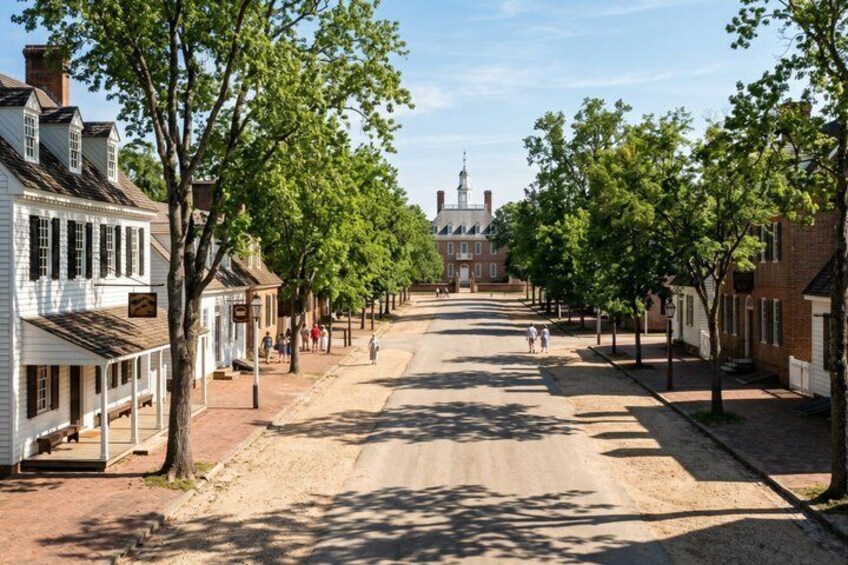 A historic street lined with white buildings, a church steeple, and a distant clock tower. 3