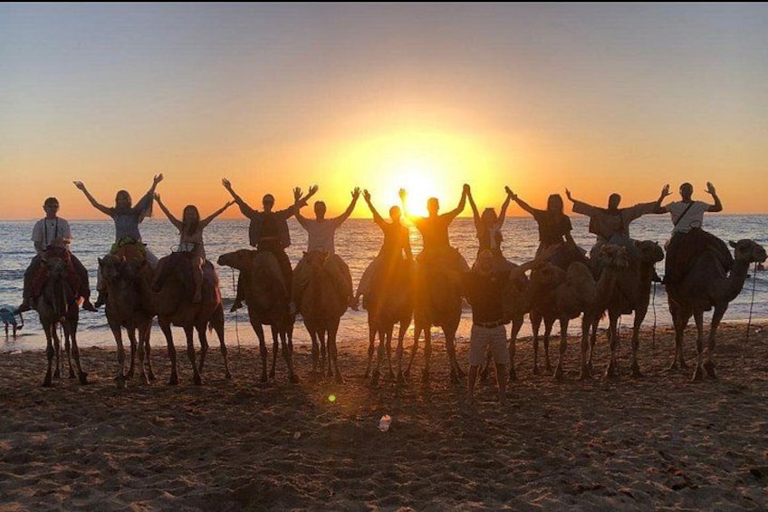 A group of people on camels at sunset on a beach. 4