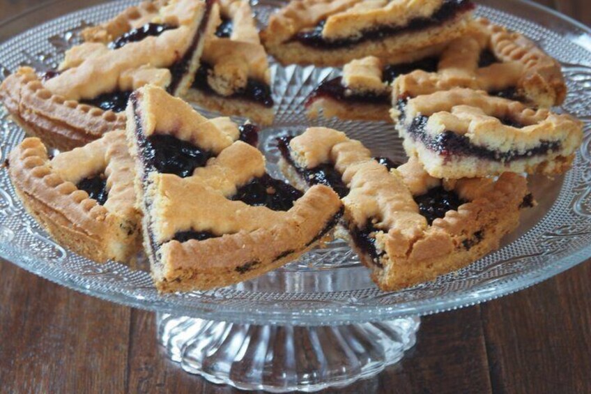 A glass pie dish with triangular fruit tarts on a wooden table. 4