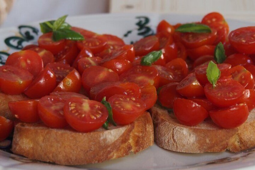 Two slices of toasted bread topped with cherry tomatoes and basil leaves. 3