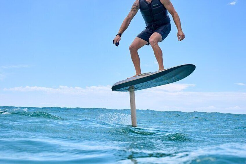 A person surfing on a wave with a clear blue sky in the background. 1