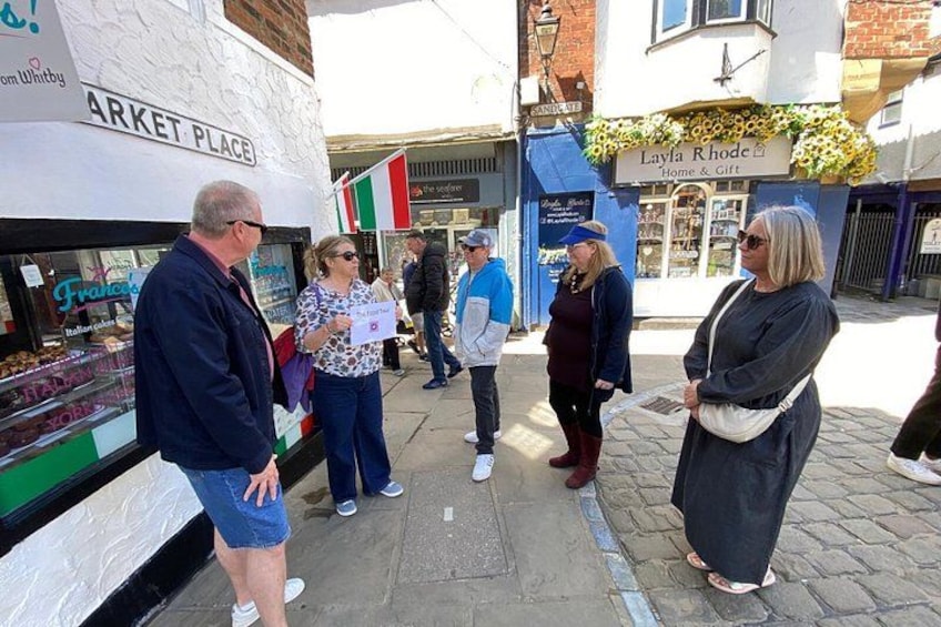 People standing in front of a market stall with a sign that reads 'MARKET PLACE.' 3