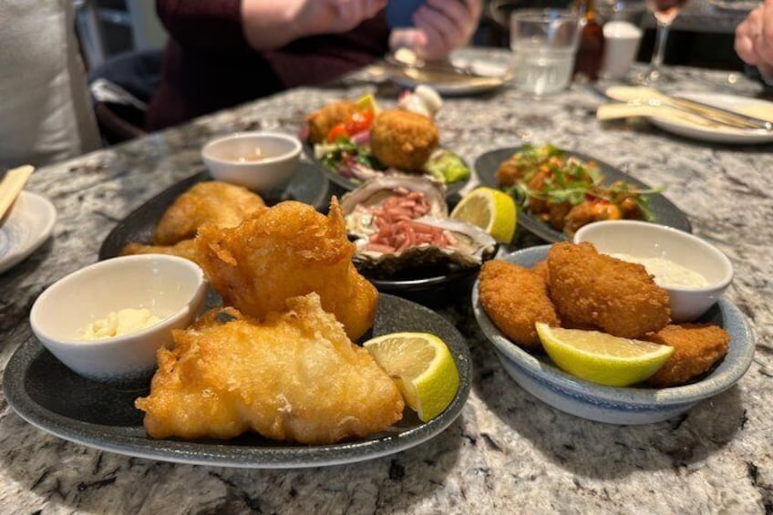 A table with various dishes including fried items, a salad, and a bowl of sauce. 3
