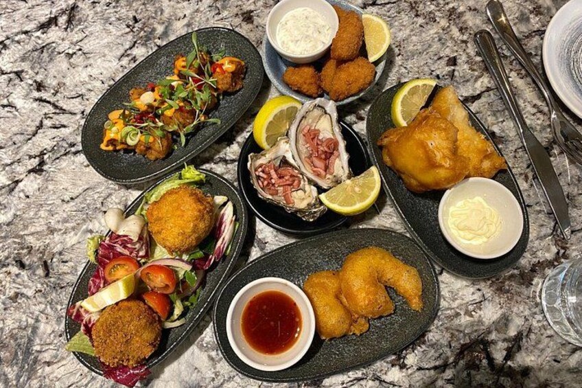 A variety of seafood dishes on plates, including fried fish, shrimp, and a salad. 1