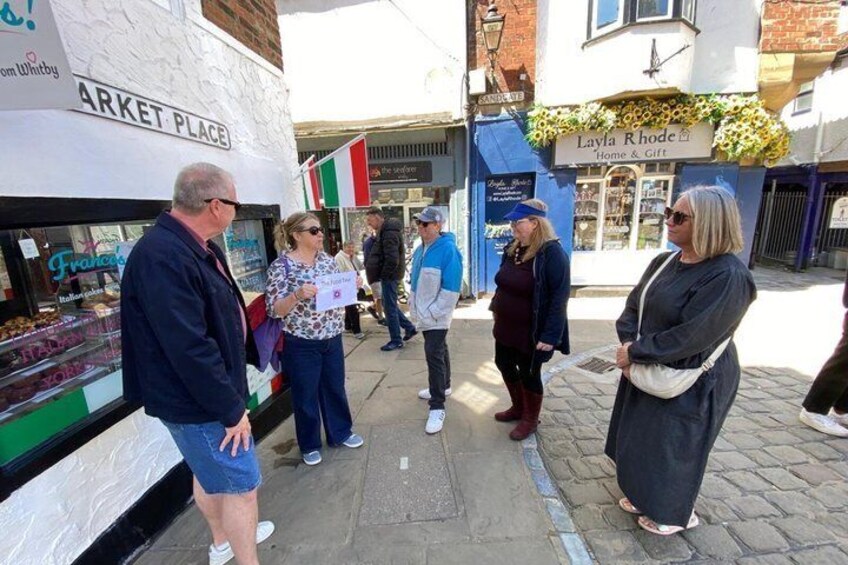 People standing in front of a market stall with a sign that reads 'MARKET PLACE.' 5