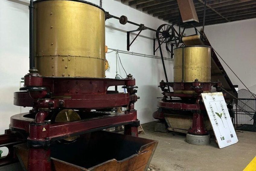 Two large brass machinery with wheels and levers, likely used for industrial purposes, in a warehouse setting. 3
