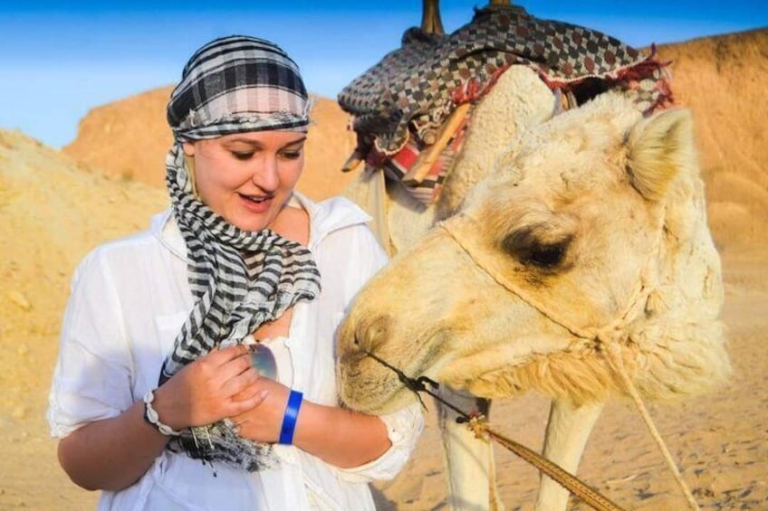 A person interacting with a camel in a desert setting. 2