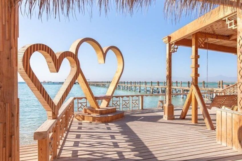 A wooden pier with heart-shaped cutouts, a wooden gazebo, and a distant pier. 3
