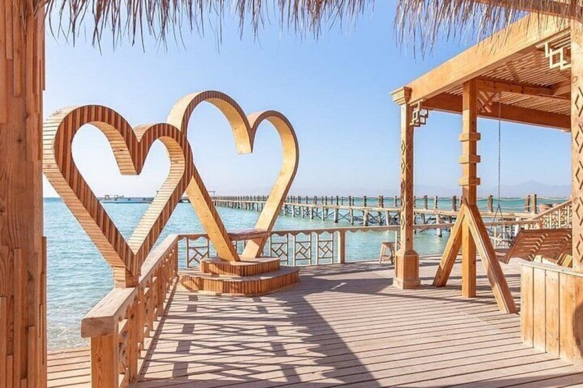 A wooden deck with heart-shaped cutouts, a pier, and a clear blue sky. 3